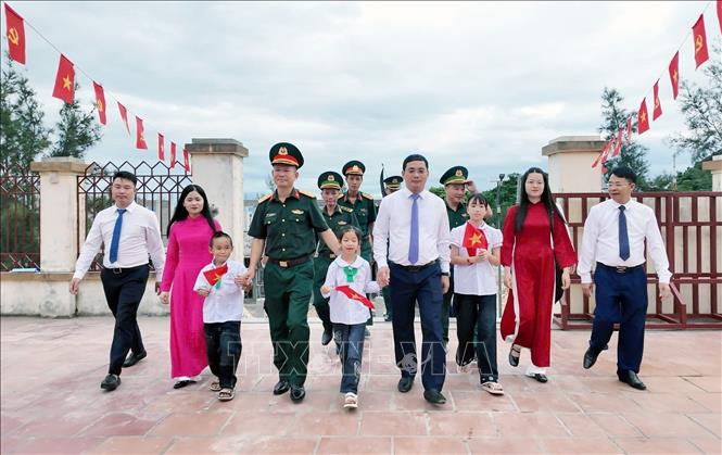 Lãnh đạo địa phương cùng cán bộ, quân dân trên đảo Trần (Cô Tô) đưa trẻ đến trường. Ảnh: TTXVN phát